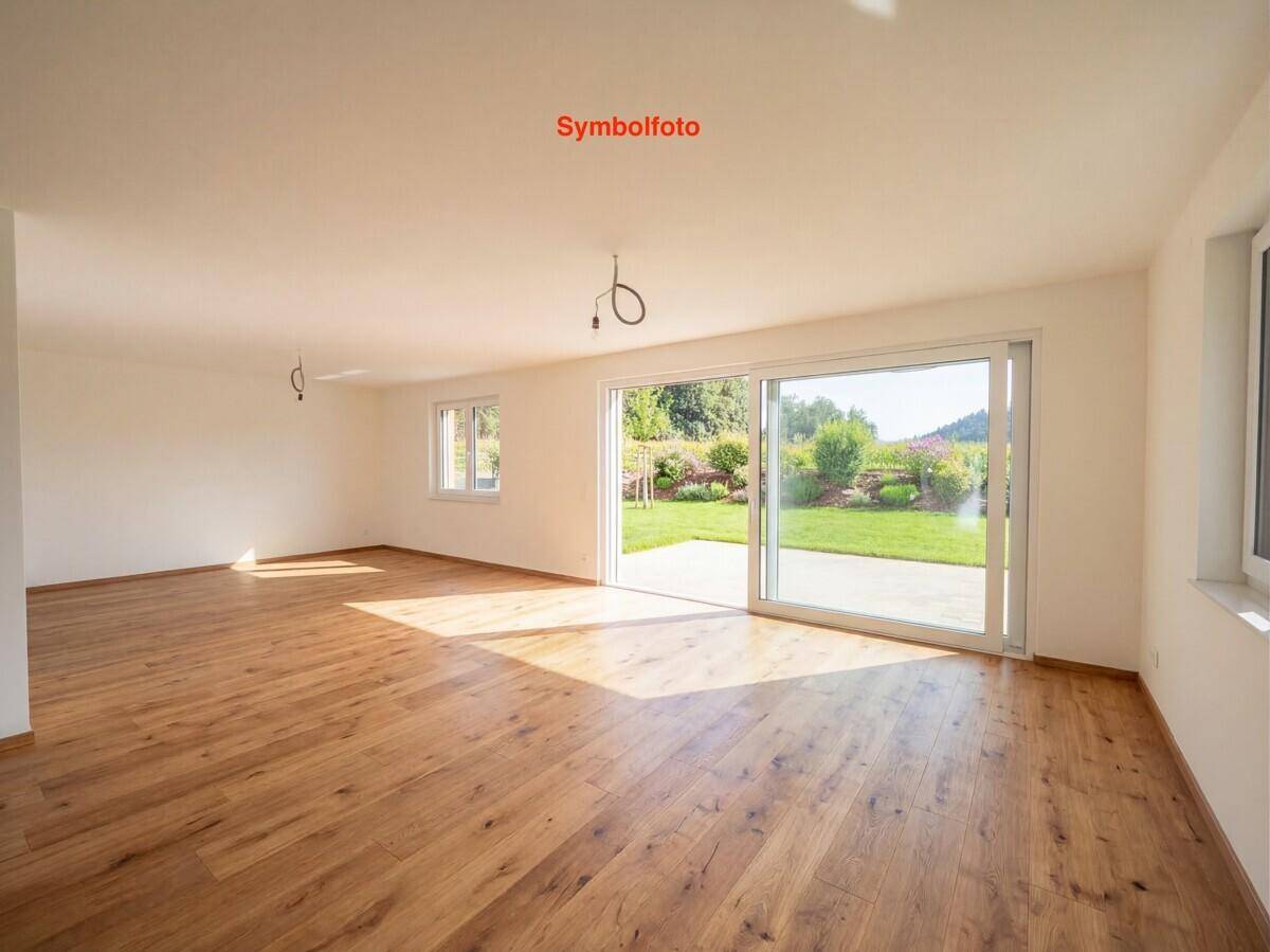 Lichtdurchflutetes Wohnzimmer mit Holzboden und weitem Blick in den grünen Garten.