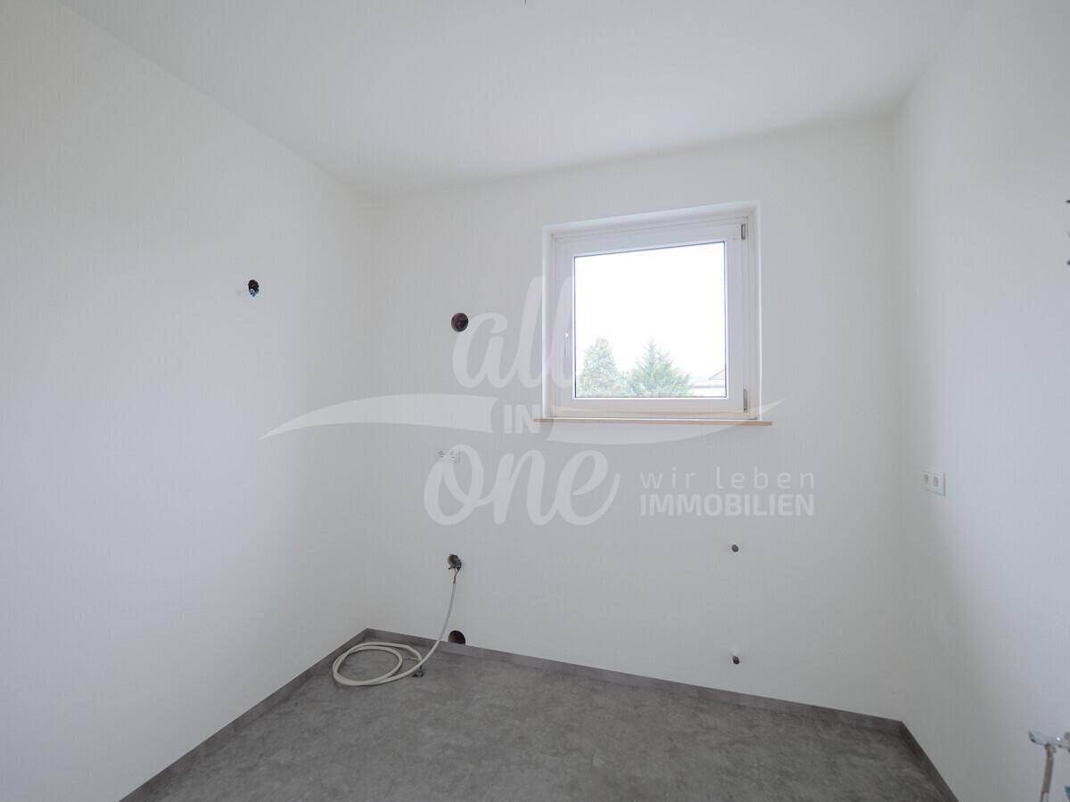 Unfertige Küche mit sichtbaren Anschlüssen und einem Fenster.
