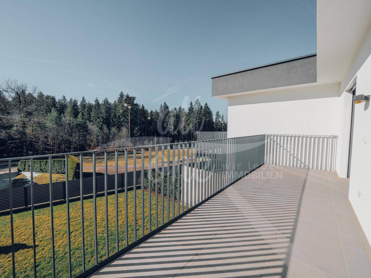 Langer Balkon mit moderner Brüstung und freiem Blick auf die umliegende Natur und Wiesen.