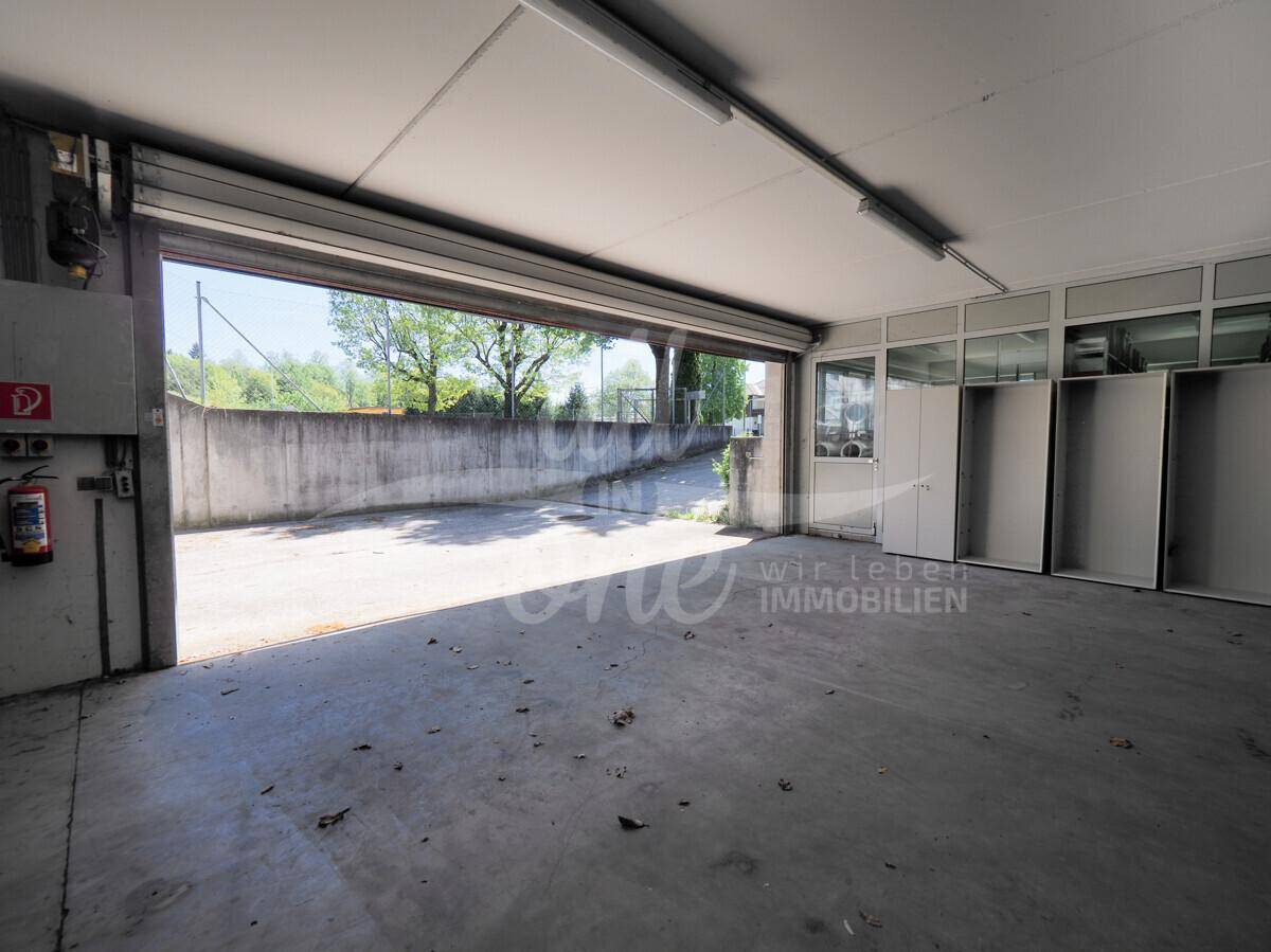 Eingangsbereich einer Tiefgarage oder Lagerhalle mit großem Rolltor und Blick ins Grüne.