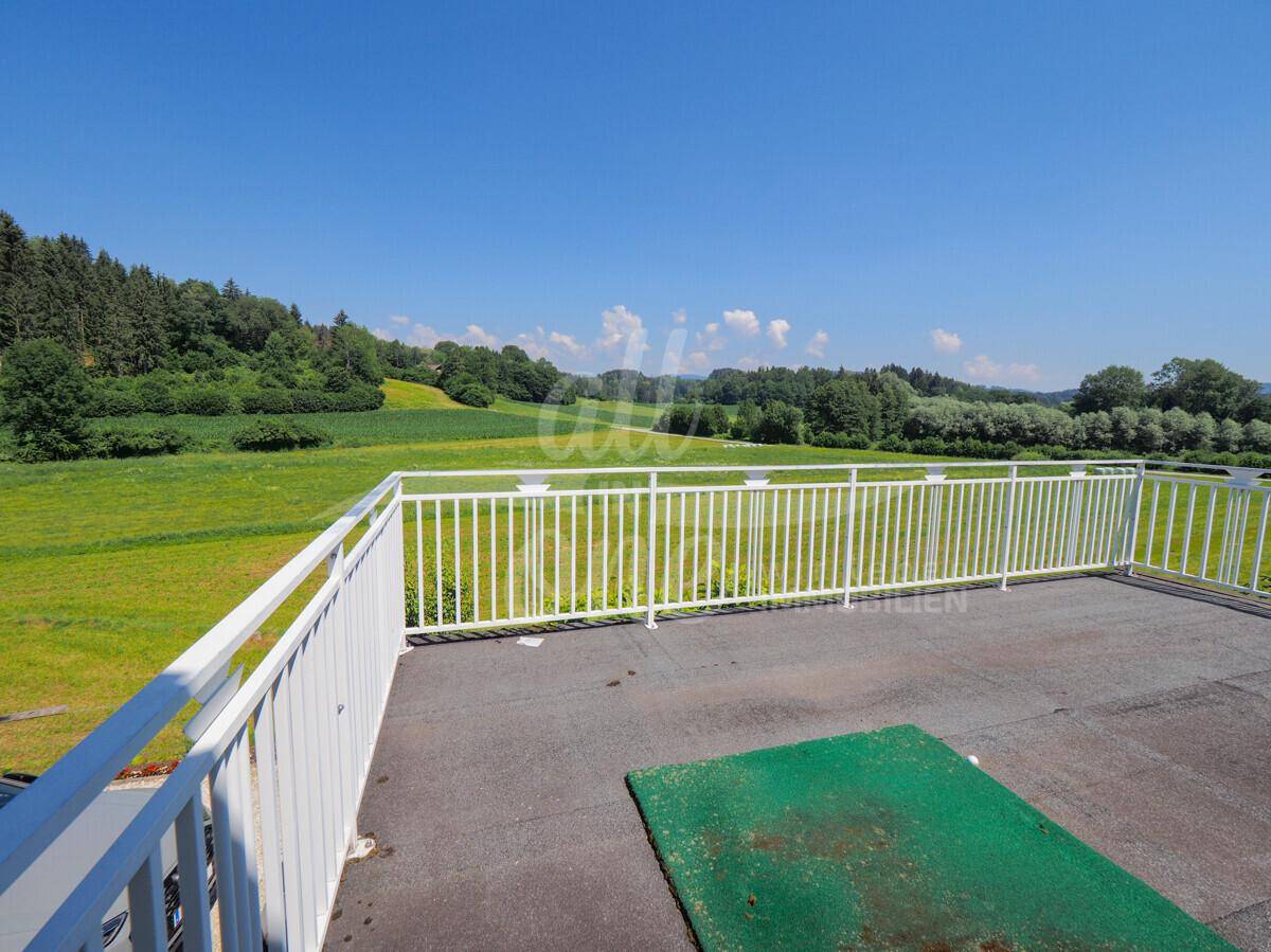 Große Dachterrasse mit weitem Blick über die grüne Landschaft und Felder.