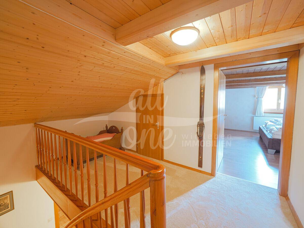 Heller Flur im Obergeschoss mit Holzdecke und Zugang zu Schlafzimmern.