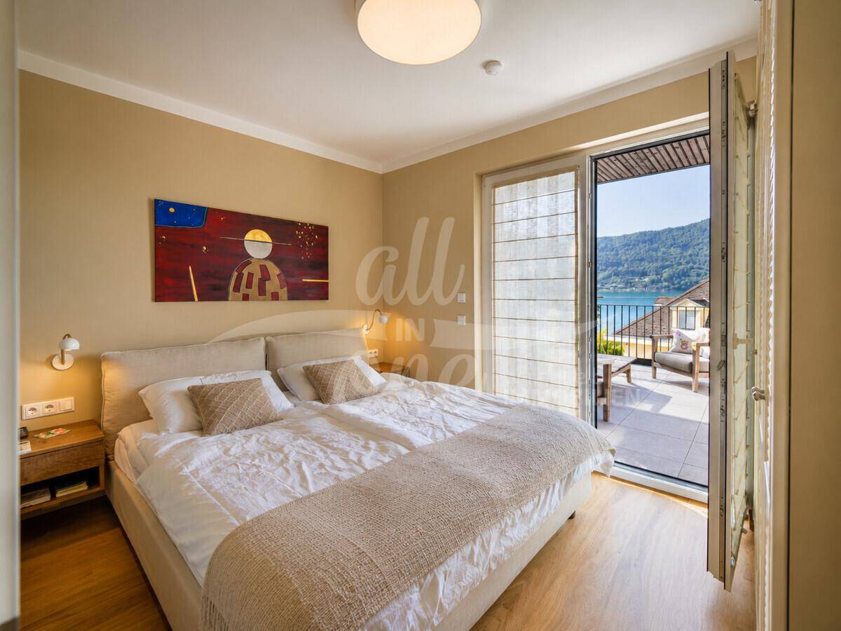 Helles Schlafzimmer mit Doppelbett, Holzboden und direktem Zugang zur Terrasse mit Seeblick.