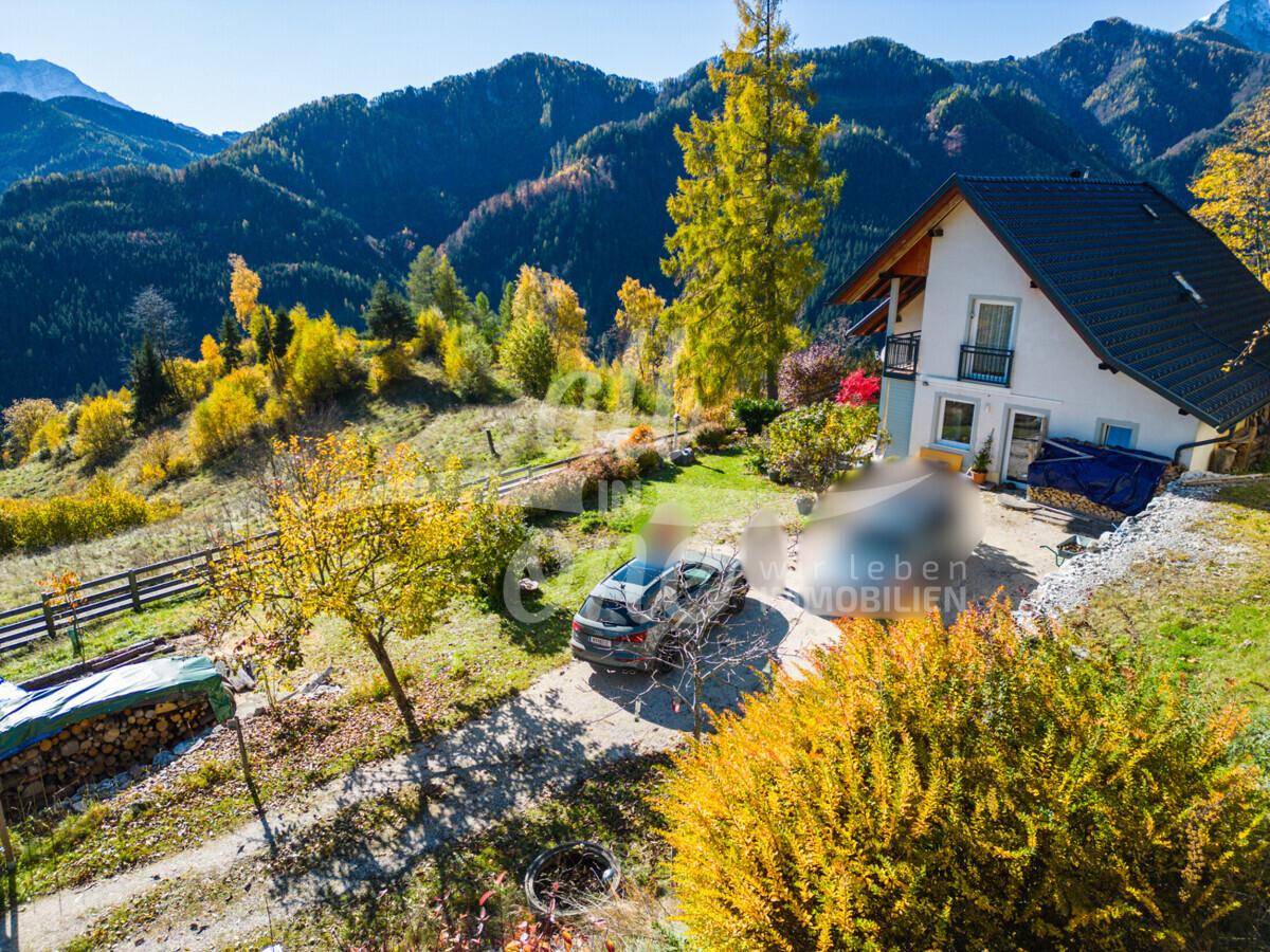 Ansicht des Hauses mit Einfahrt, geparktem Auto und malerischem Blick auf die Berge.