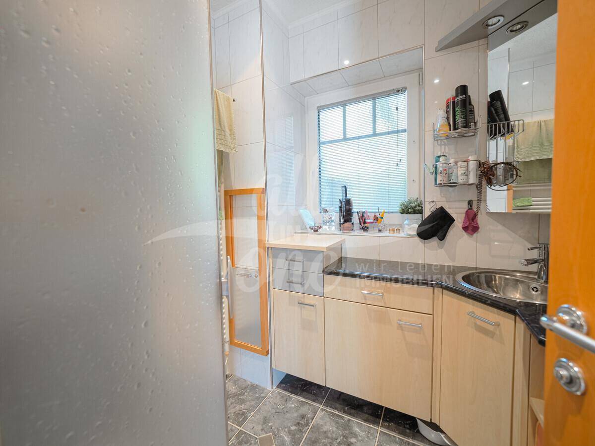 Funktionales Badezimmer mit Duschkabine, Einzelwaschbecken, Spiegelschrank und Fenster.