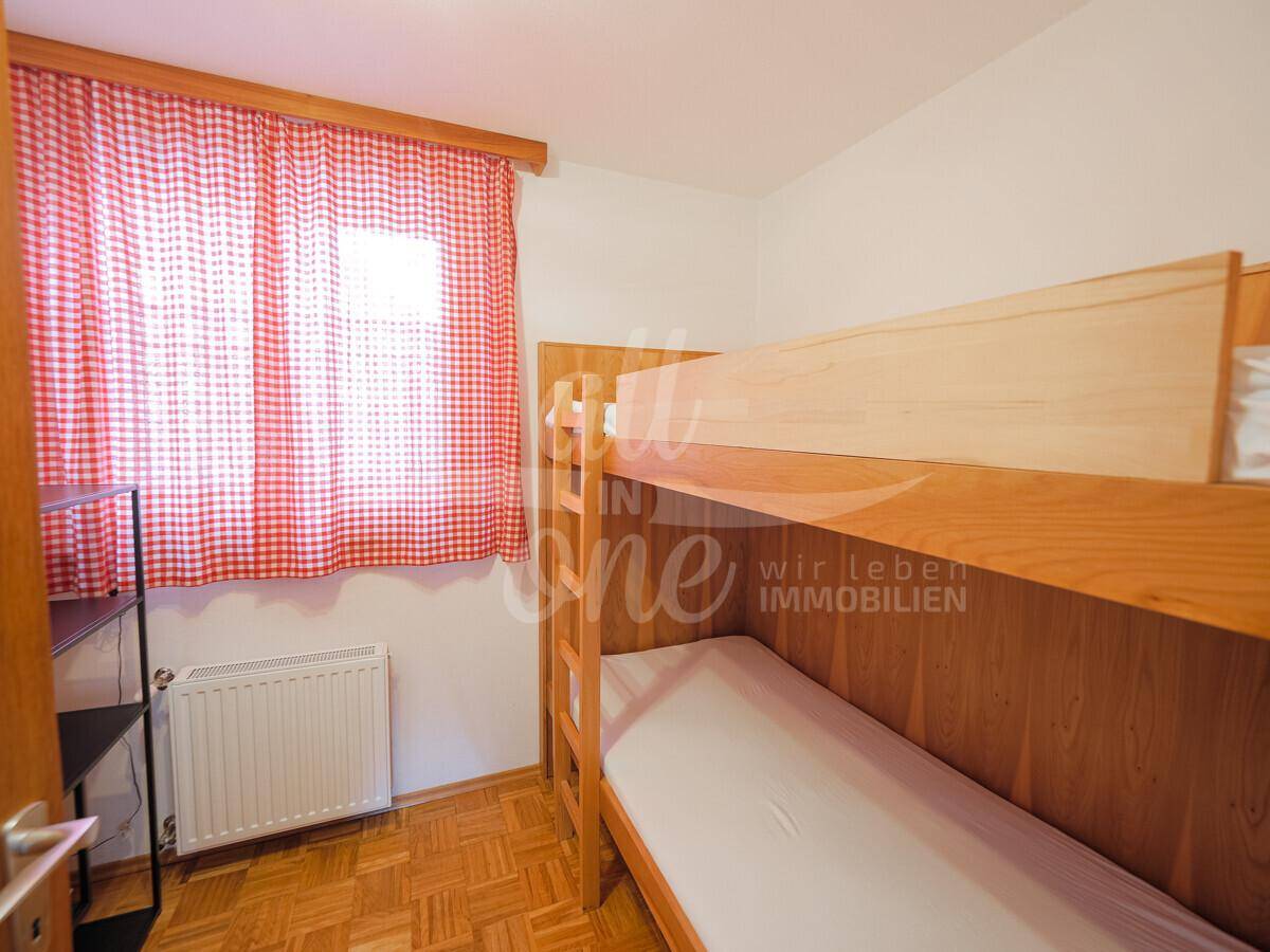Kinderzimmer mit Etagenbett und karierten Vorhängen.