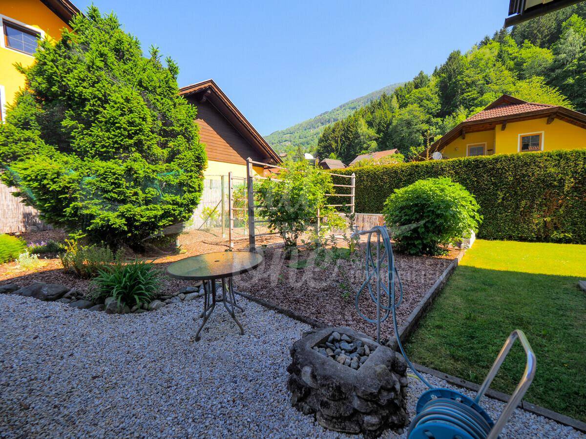 Idyllischer Gartenabschnitt mit Rasenfläche, Feuerstelle und üppigen Hecken.