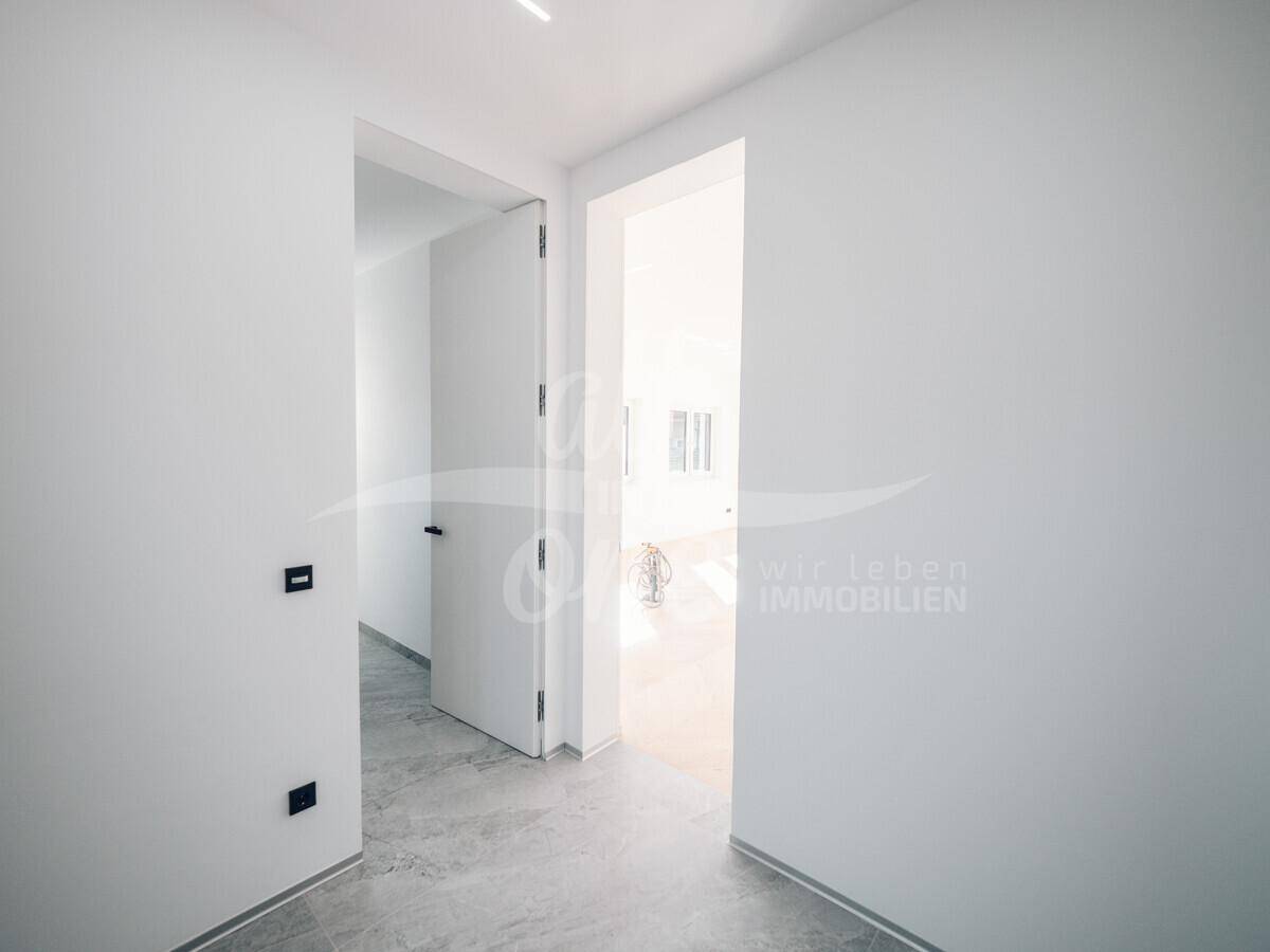 Heller Flur mit modernen Fliesen und Zugang zu weiteren Räumen.