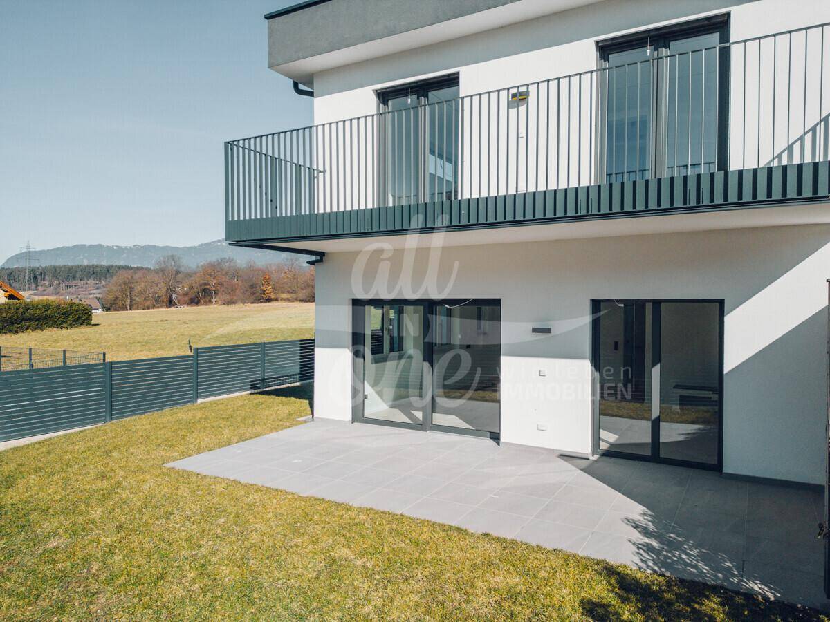 Sonniger Terrassenbereich mit Zugang zum Garten und Balkon im Obergeschoss.