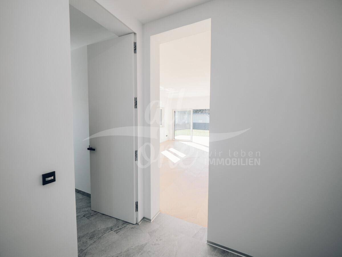 Heller Flur mit Blick in den offenen Wohnbereich mit Parkettboden.