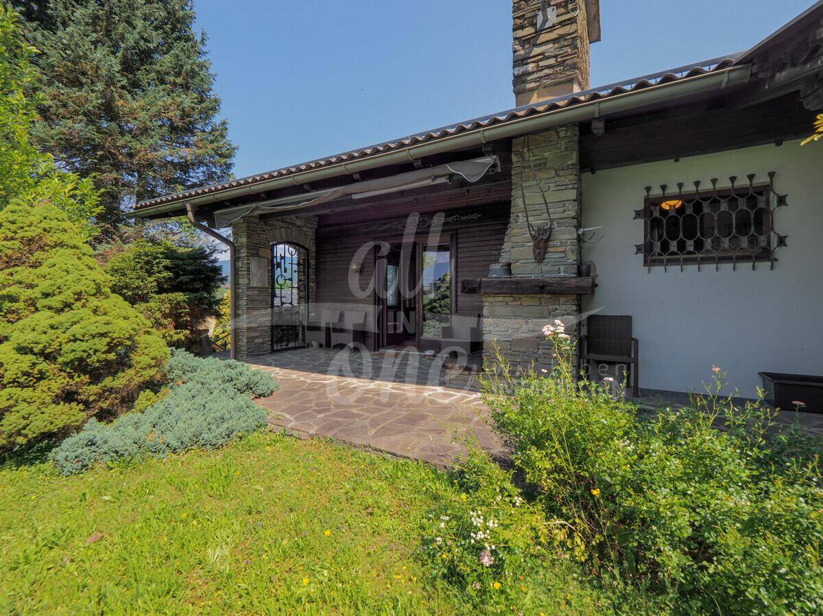 Geräumige überdachte Terrasse mit Steinkamin und direktem Zugang zum grünen Garten.