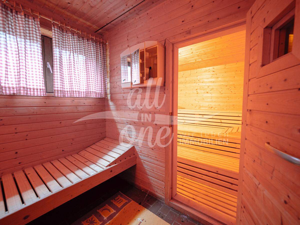 Traditionelle Holzsauna mit Sitzbänken und einem kleinen Fenster für natürliche Belüftung.