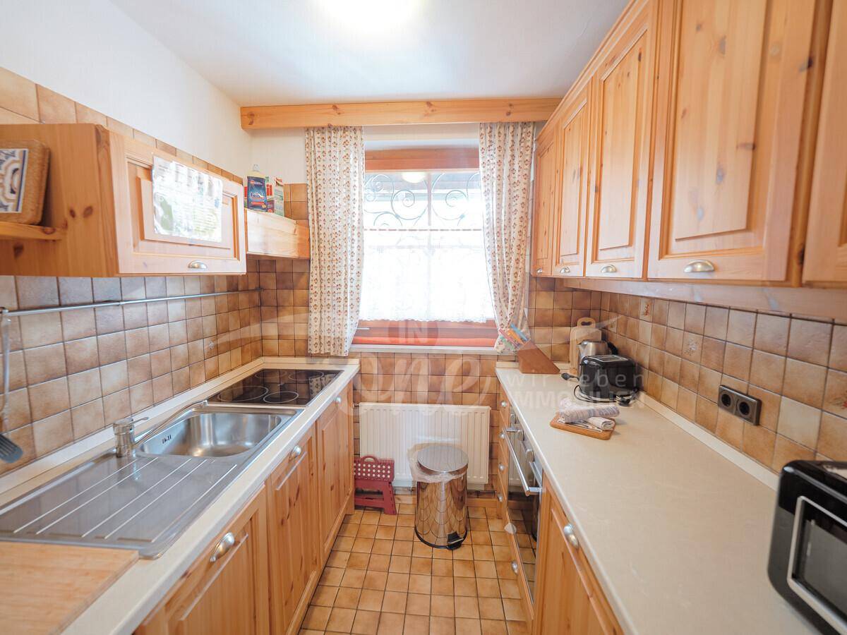 Funktionale Küche im Landhausstil mit Holzschränken und Fliesenboden.