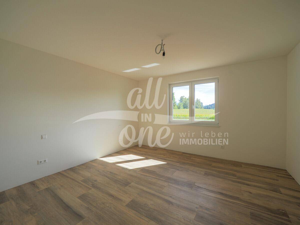 Geräumiges Schlafzimmer mit Holzboden und großem Fenster, das viel Tageslicht hereinlässt.