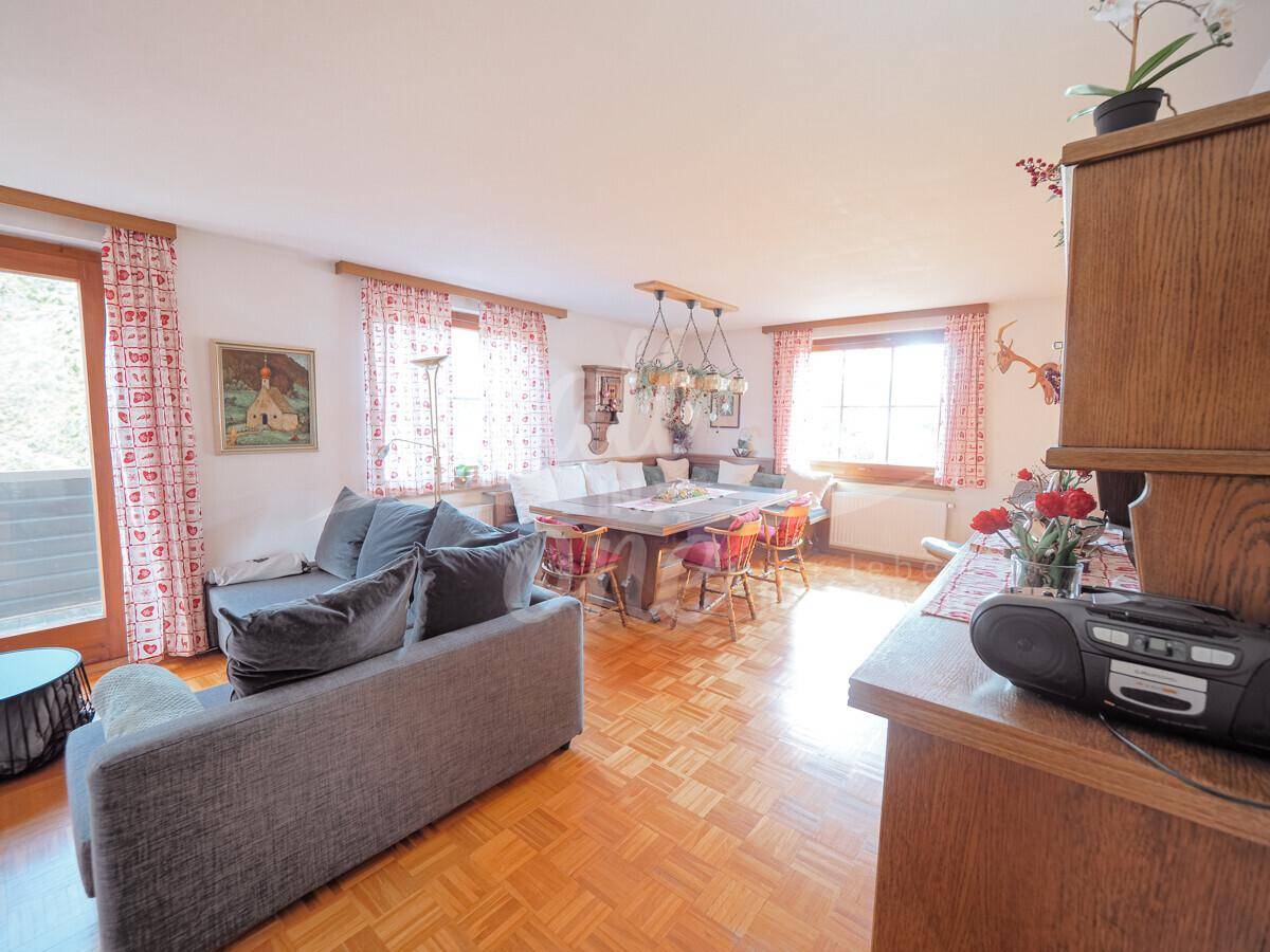 Gemütlicher Wohn-Essbereich mit Parkettboden, großem Esstisch und Zugang zum Balkon.