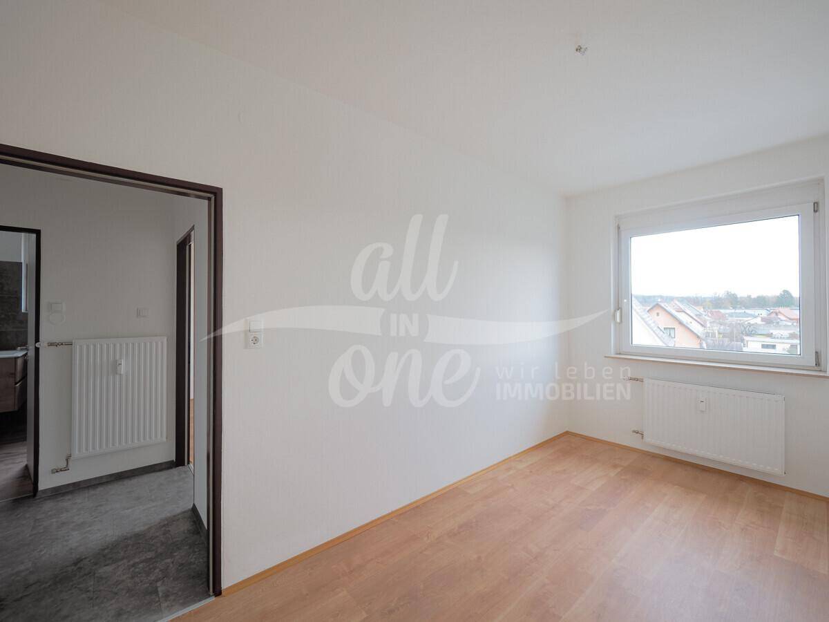 Geräumiges Schlafzimmer mit Laminatboden und Zugang zu einem weiteren Raum.