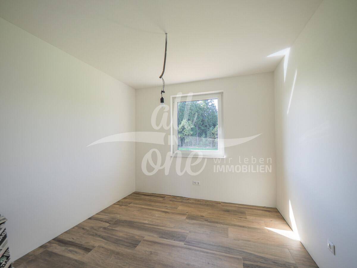 Gemütliches Zimmer mit Holzboden und einem Fenster, das einen ruhigen Ausblick in die Natur ermöglicht.