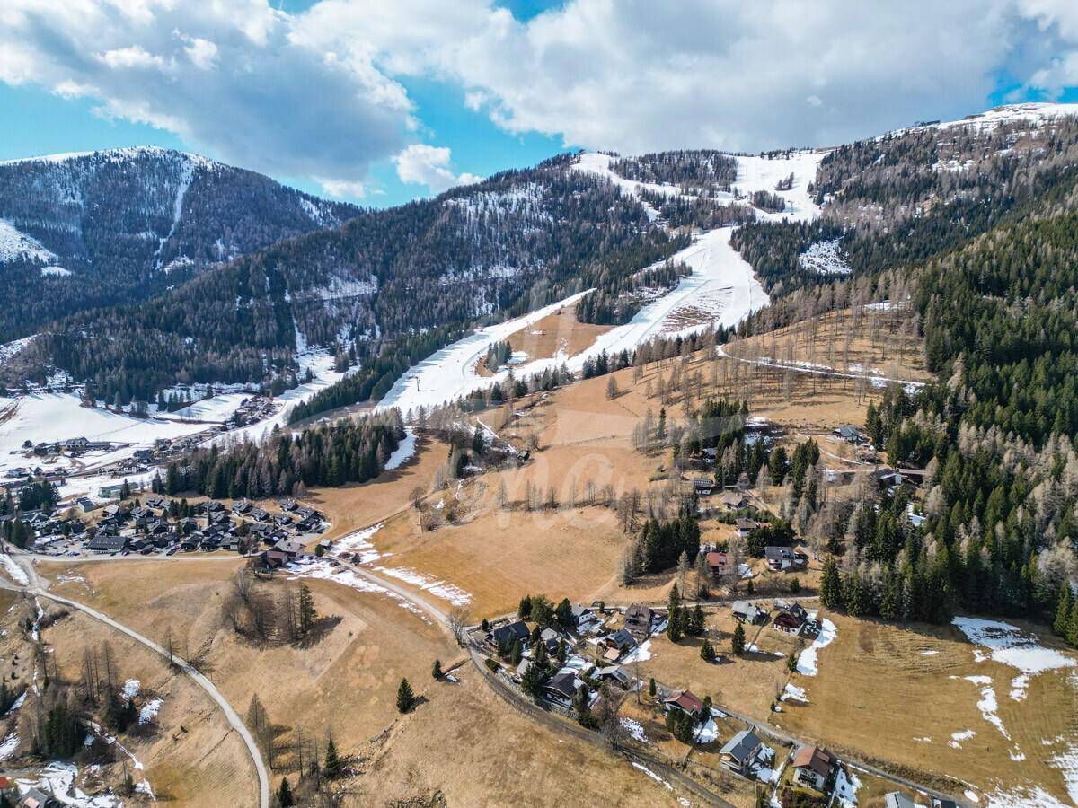 Weitläufige Luftaufnahme der Berglandschaft mit Skigebiet und Siedlungen.