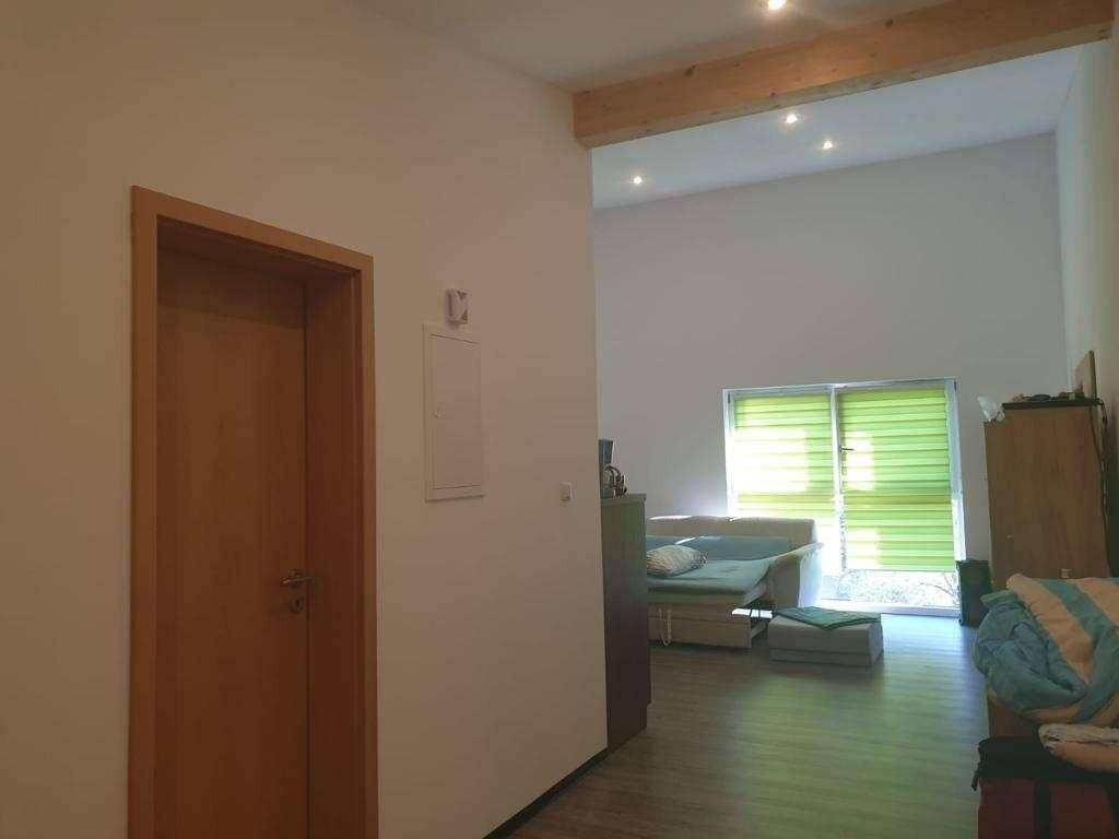 Heller Wohnbereich mit Holzbalken an der Decke und großen Fenstern, die viel Licht hereinlassen.