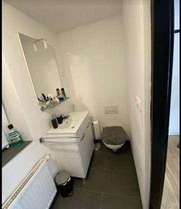 Kleines Gäste-WC mit Waschbecken, Toilette und dunklen Bodenfliesen.