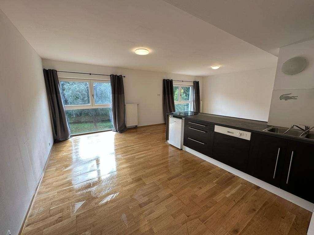 Heller, offener Wohnbereich mit Küchenzeile und großen Fenstern mit Blick ins Grüne.
