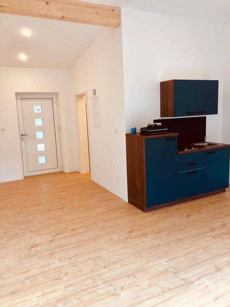 Kompakte Küchenzeile mit blauen Schränken, Holzarbeitsplatte und Holzboden.