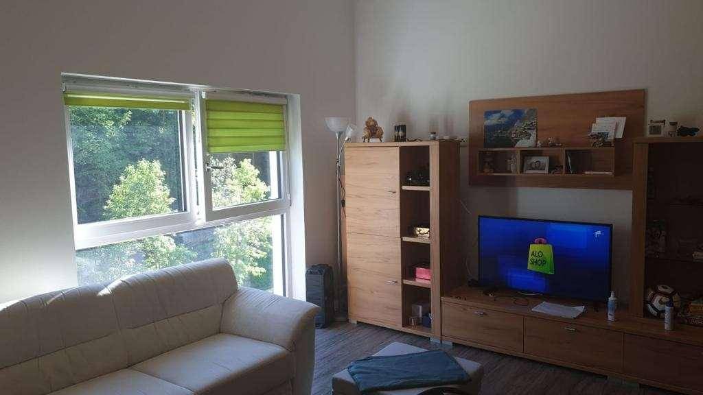 Gemütliches Wohnzimmer mit Sofa, TV-Möbeln und Blick ins Grüne durch das Fenster.