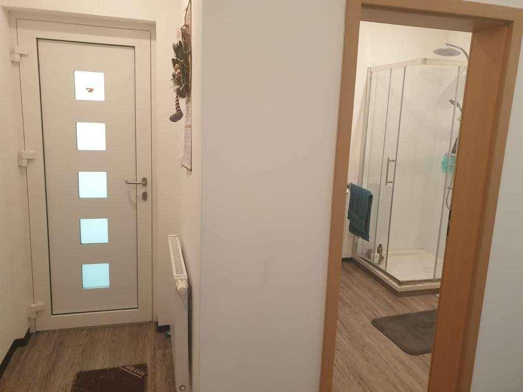 Heller Eingangsbereich mit moderner Tür und Blick in ein Badezimmer mit Dusche.