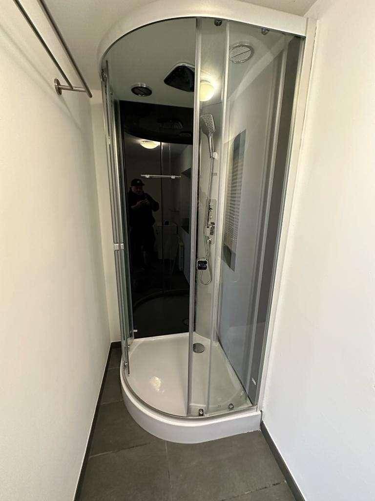 Moderne Duschkabine mit Glaswänden und Regendusche in einem hellen Badezimmer.