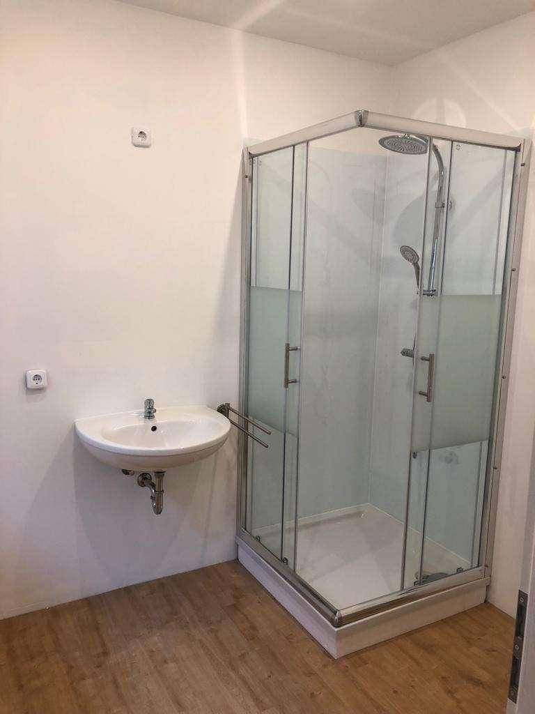 Badezimmer mit Duschkabine und Waschbecken, bereit zur Fertigstellung.