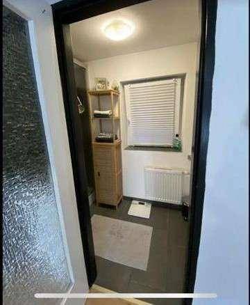 Badezimmer mit Fenster, Heizung und dunklen Fliesen, bereit zur individuellen Gestaltung.