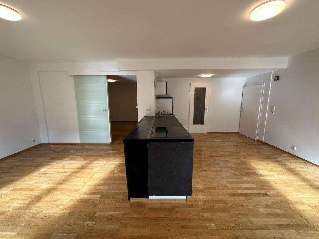 Geräumiger, leerer Wohnbereich mit Kücheninsel und Holzboden, bereit zur Einrichtung.