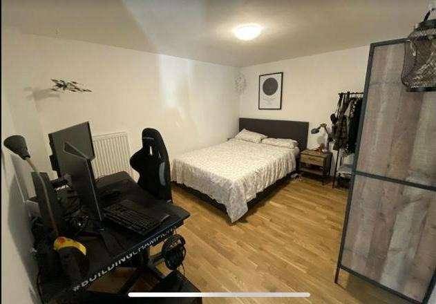 Schlafzimmer mit Doppelbett, Schreibtisch und rustikalem Holzschrank, funktional eingerichtet.