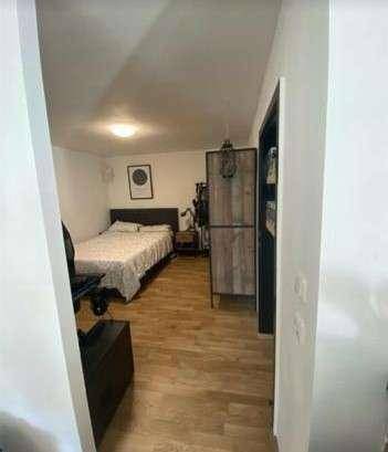 Blick vom Flur in ein Schlafzimmer mit Doppelbett und Holzboden, hell und einladend.
