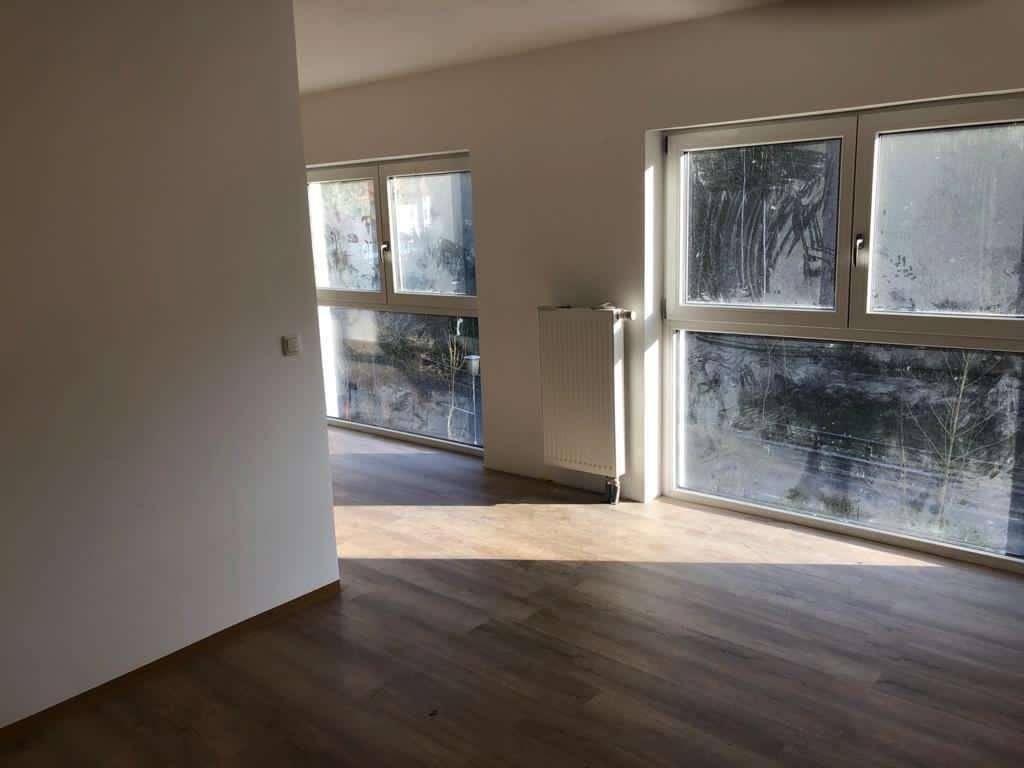 Heller, unmöblierter Raum mit großen Fenstern und Holzboden, ideal für individuelle Gestaltung.