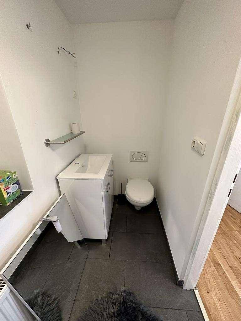 Kleines Gäste-WC mit Waschbecken, Toilette und dunklen Bodenfliesen.