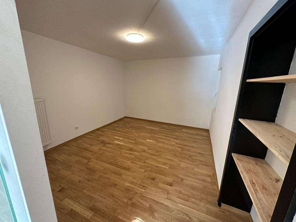 Leerer Raum mit Holzboden und Regal, ideal als Arbeits- oder Gästezimmer.