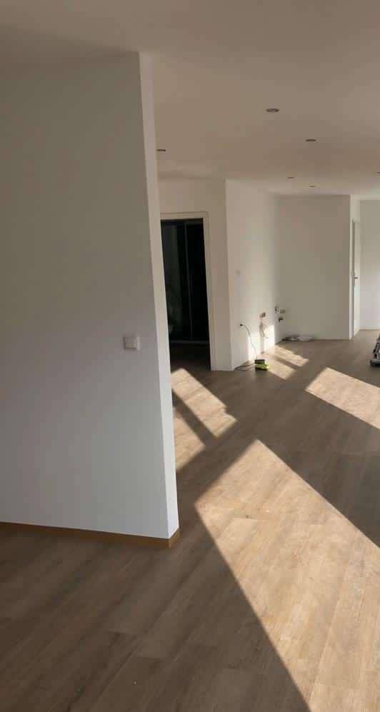 Heller Flurbereich mit Holzboden und Sonnenlicht, das durch die Fenster fällt.