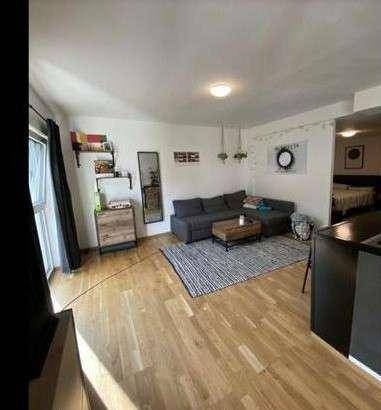 Gemütlicher Wohnbereich mit Sofa, Teppich und Blick ins Grüne durch große Fenster.