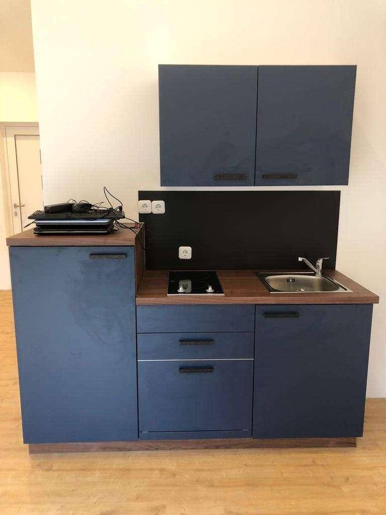 Detailansicht einer kleinen Küchenzeile mit blauen Schränken und integriertem Kochfeld.