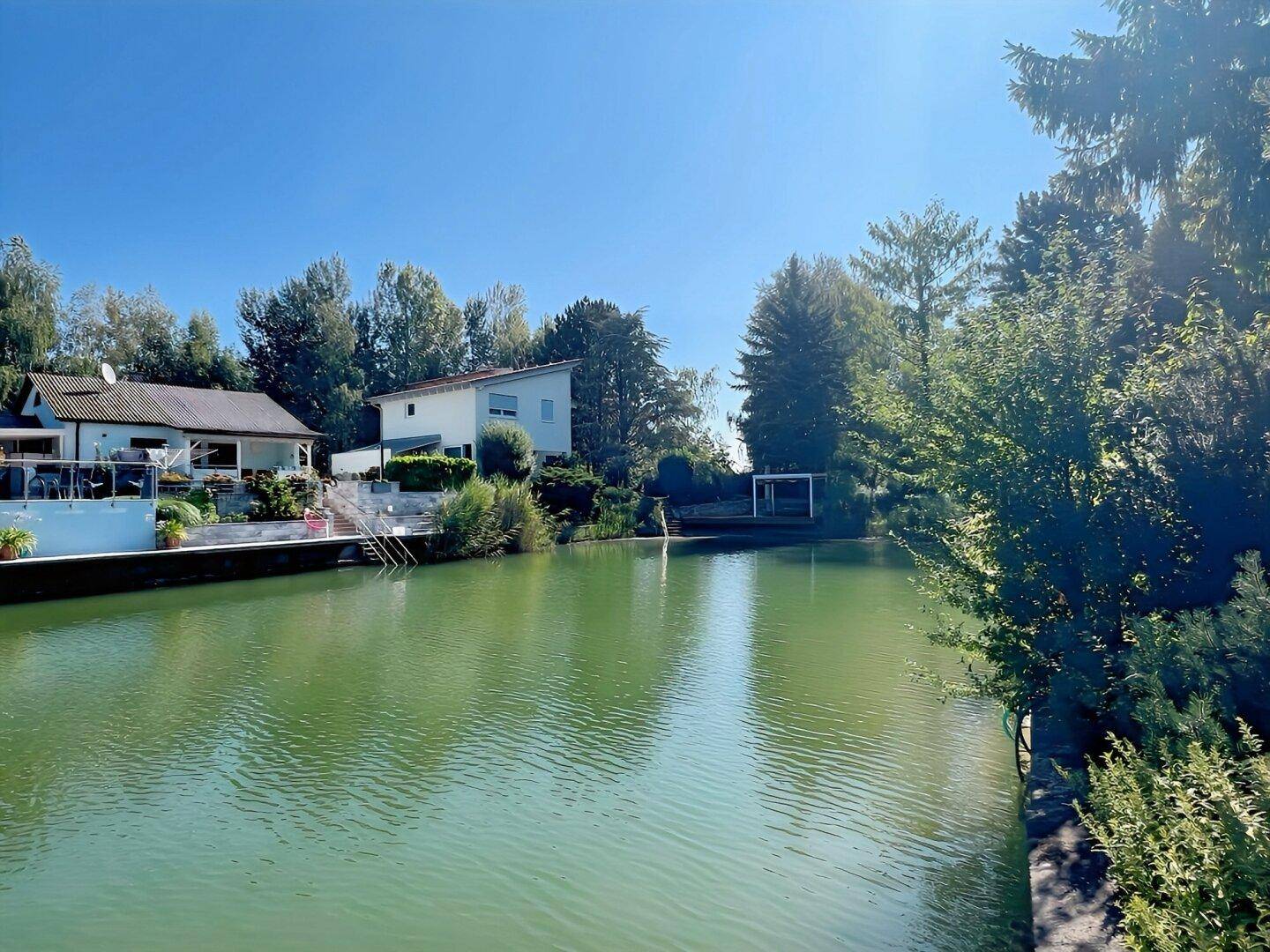 Panoramablick auf den See mit Häusern am Ufer und üppiger grüner Landschaft.