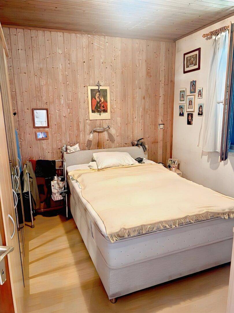 Schlafzimmer mit Holzwänden, Parkettboden und Doppelbett.