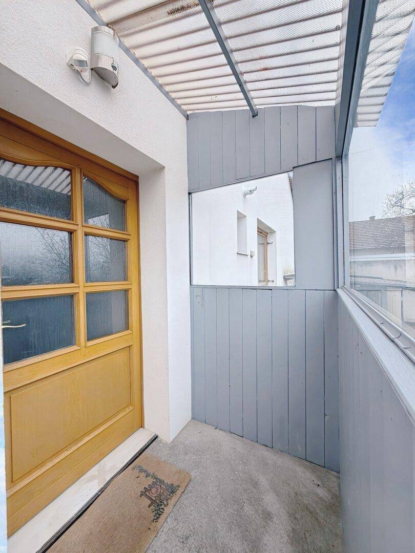 Überdachter Eingangsbereich mit Holztür und seitlicher Verglasung, geschützt vor Witterung.