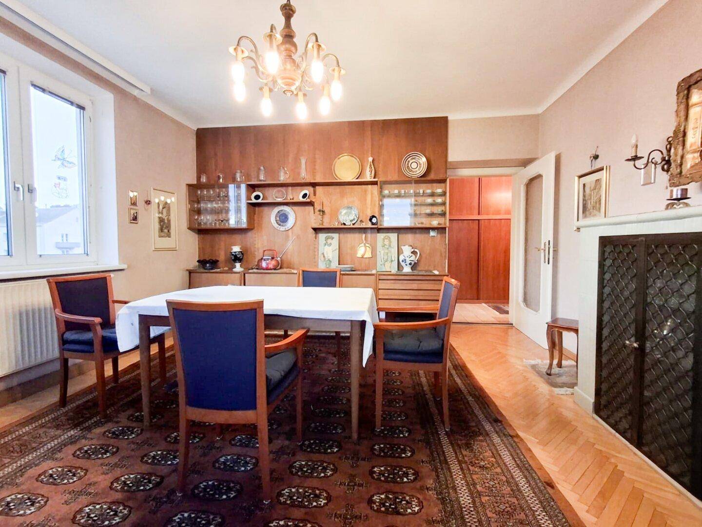 Geräumiges Esszimmer mit traditionellem Holzwandschrank, Parkettboden und Kronleuchter.
