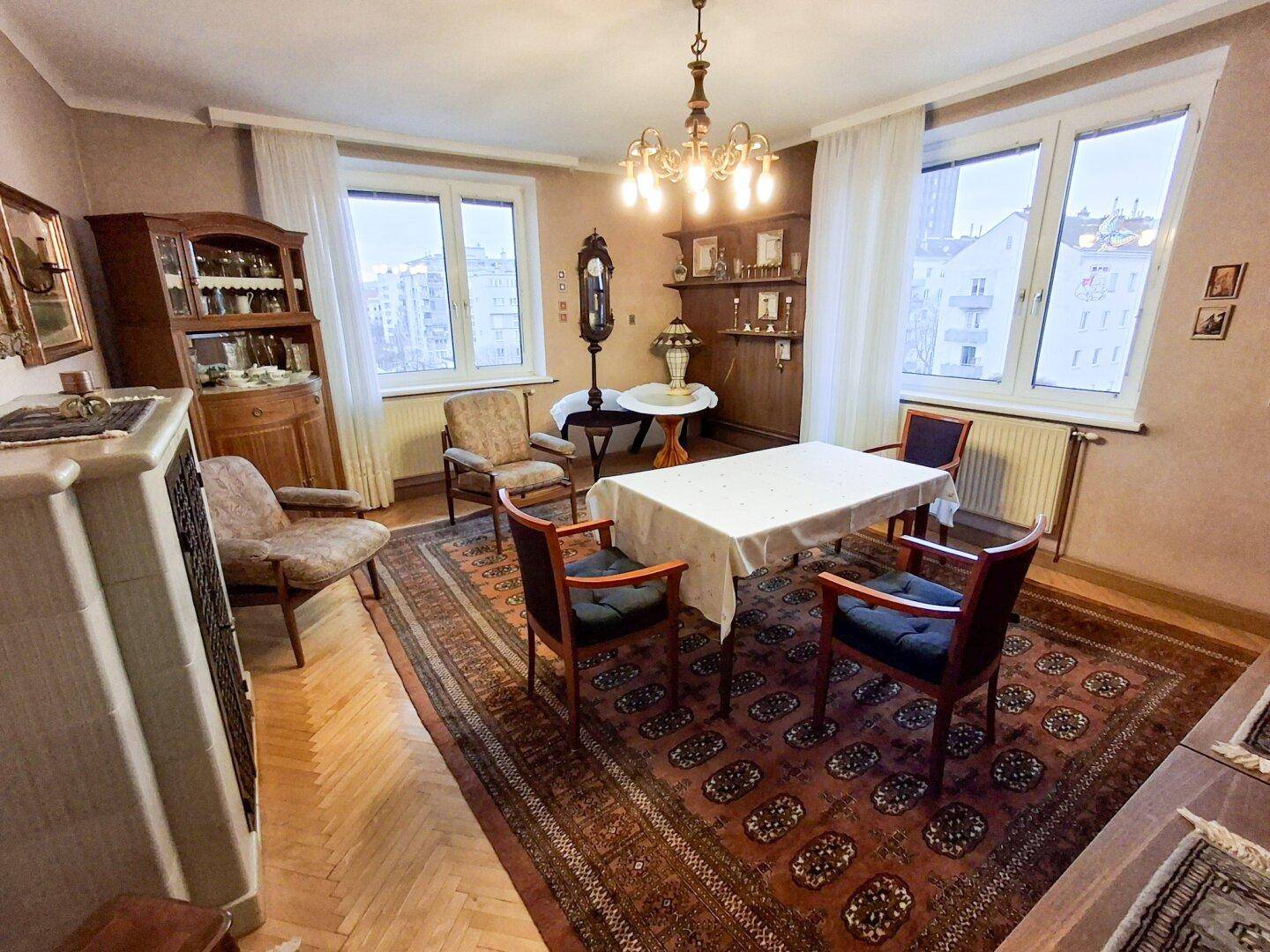 Helles Esszimmer mit zwei großen Fenstern, Parkettboden und traditionellen Möbeln.