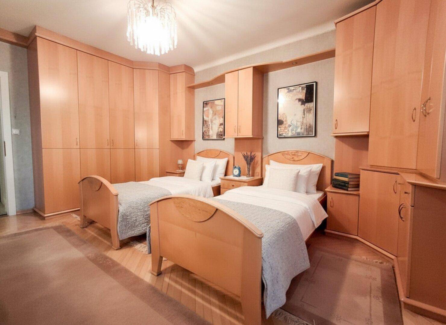 Schlafzimmer mit zwei Einzelbetten und maßgefertigten Holzschränken.