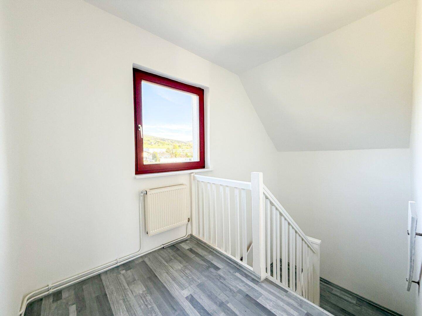 Heller Treppenbereich mit Fenster und Zugang zu den oberen Etagen.