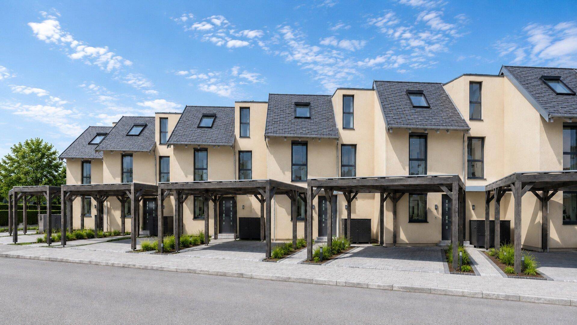Reihe moderner Reihenhäuser mit Carports und gepflasterten Zufahrten unter blauem Himmel.
