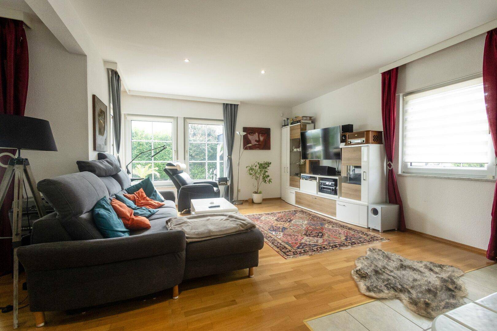 Gemütliches Wohnzimmer mit Holzboden, großem Sofa und Blick in den Garten.
