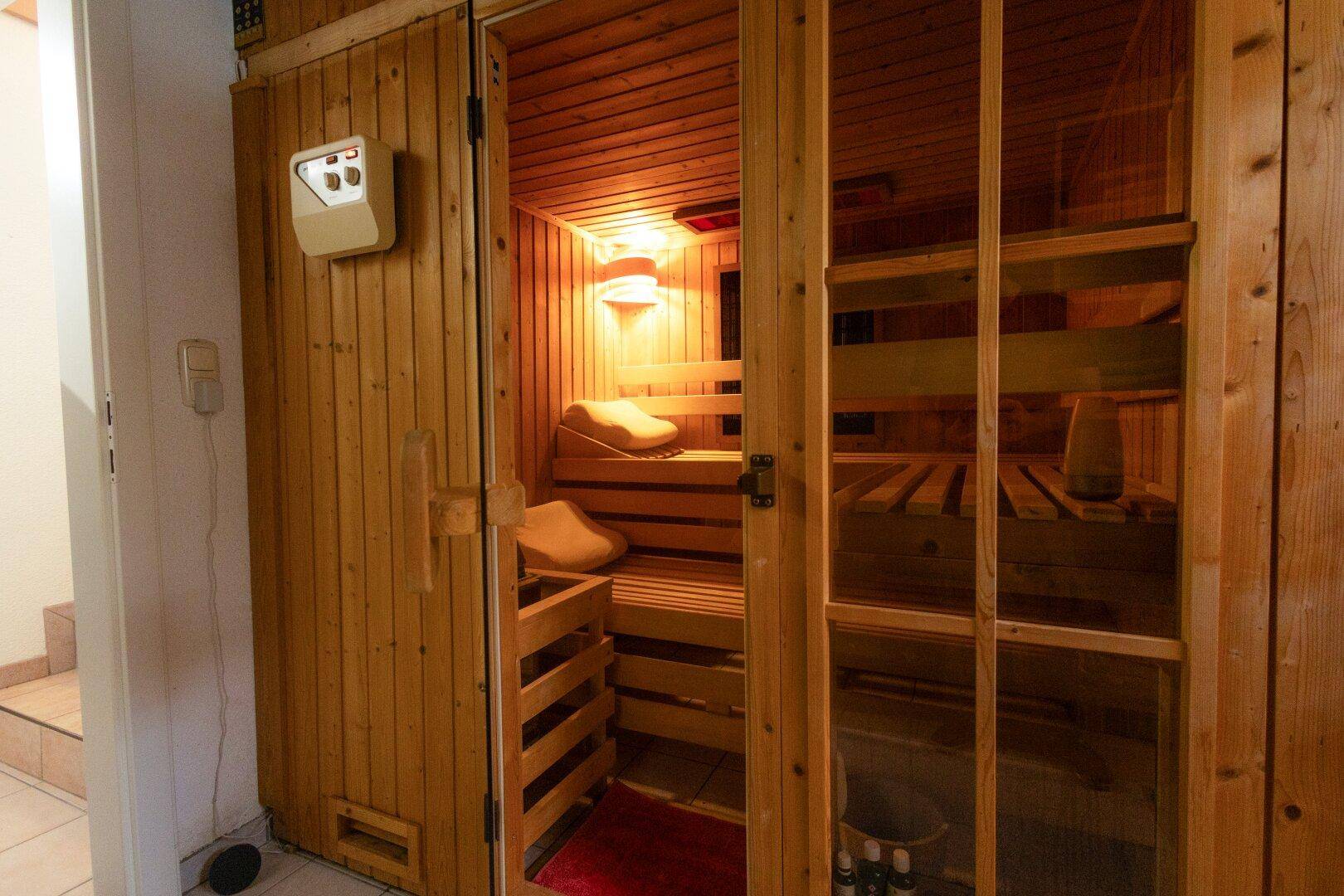 Gemütliche Holzsauna mit Bänken und Steuerungselementen für entspannende Momente.